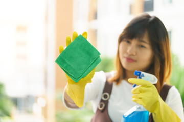 Woman housekeeper cleaning the mirror with green cloth.