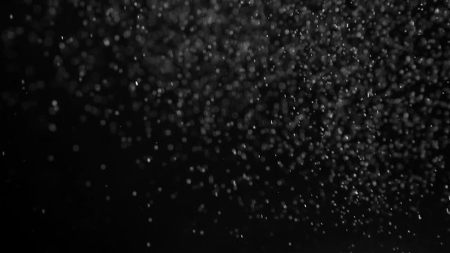 Chaotic Motion of Weightless Particles. Fine white particles slowly and chaotically soar in the air against a black background. Slow Motion at a rate of 240 fps
