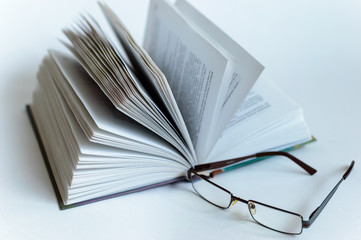 Open book lies on a white background in isolation on a white background. Glasses