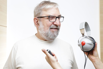 Starszy mężczyzna z słuchawkami do badania słuchu - obrazy, fototapety, plakaty