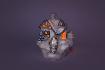 Decorative house with a candle inside. The candle burns. Against a dark background