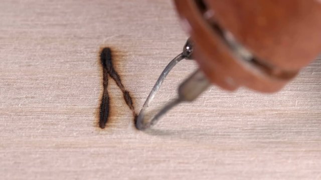 a soldering iron on wood,man burns patterns and symbols