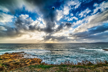 Obraz premium Dramatic sky over Alghero rocky shore