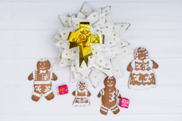 Top view of homemade gingerbread Christmas tree with cute gingerbread family with gifts on white wooden desk