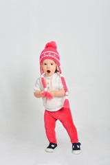 Little girl in a cap and sweater. Isolated on a gray background.