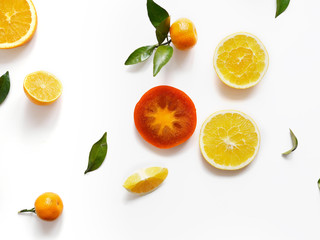 Creative flat layout of fruit, top view. Sliced orange, lemon, persimmon, tangerine, green leaves isolated on white background. Food wallpaper, composition pattern of fresh fruits.