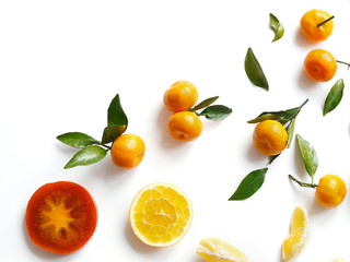 Creative flat layout of fruit, top view. Sliced orange, lemon, persimmon, tangerine, green leaves isolated on white background. Food wallpaper, composition pattern of fresh fruits.