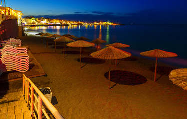 Beautiful evening with night shore with a beach and umbrellas and highlighted with bright colorsin Hersonissos bay Crete, Greece