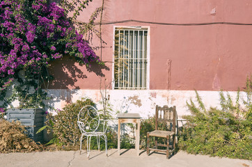 Fototapeta na wymiar Beautiful scene of two different chairs with a table in a terrace. Flowers of bougainvillaea in a farmhouse