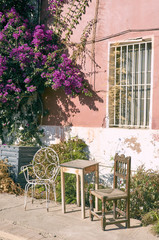 Beautiful scene of two different chairs with a table in a terrace. Flowers of bougainvillaea in a farmhouse