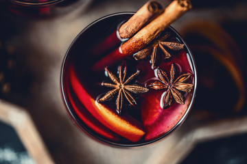 Christmas hot mulled wine in a glass with spices and citrus fruit. Mulled wine with cinnamon, anise and orange.  - obrazy, fototapety, plakaty