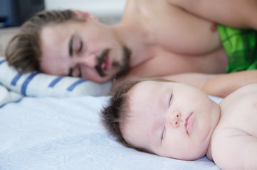 sleeping parent and baby in the morning lying on bed together, happy family
