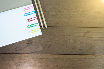 Paper clips on notebook with pencils on wooden table. Concept school supplies.