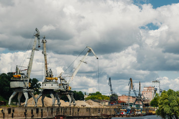 Fototapeta na wymiar Cranes in the port, harbor cranes, sea cranes unload the barge with sand