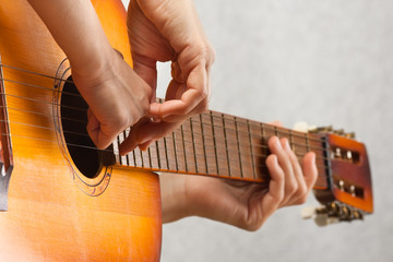 hands of adult helping child to play acoustic guitar