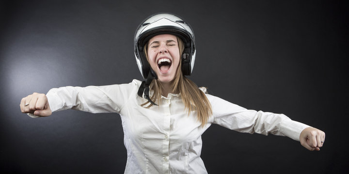 Ragazzina con il casco simula felice la guida di una moto - sfondo nero