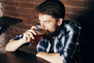 A young guy with a beard drinks beer in a bar