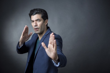 Uomo moro in giacca fa una mossa di Karate con aria aggressiva - sfondo nero