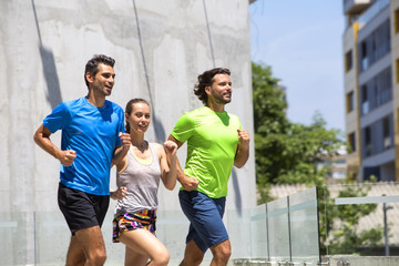 Two young men and woman running in urban enviroment