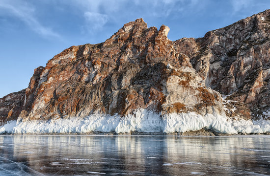 red cliff, bordered by white ice on lake Baikal