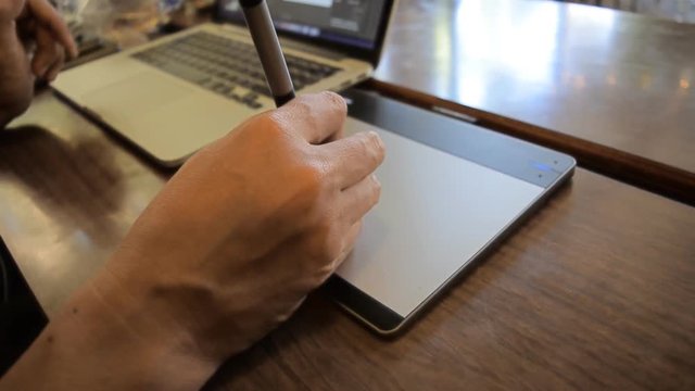 Digital business and design concept.Focus human 's hand is working with drawing by pen tablet for a laptop computer, Selective soft focus shot (Full HD,1080p 60fps).