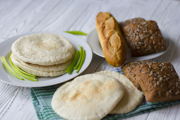 white and black bread and baguette on a wooden table