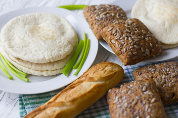 white and black bread and baguette on a wooden table