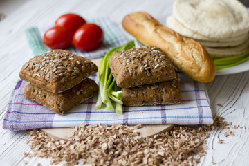 fresh bread with sunflower seeds, baguettes and tomatoes on a wooden table