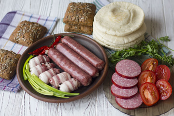 bacon, sausage, bread, parsley on a wooden table