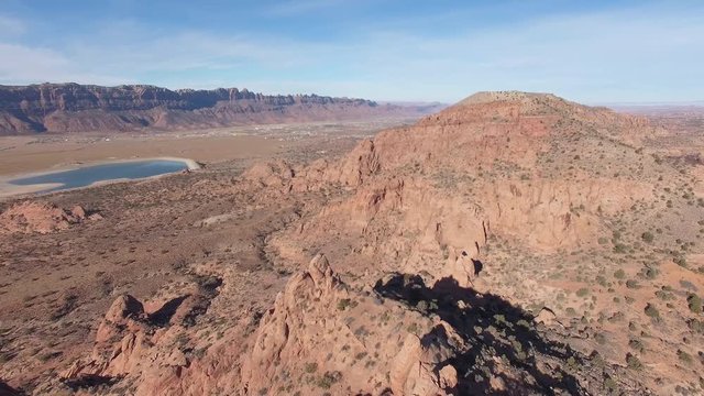 Aerial view of red rock desert landscape in Moab Utah flying backwards over tops of sandstone rock formations.