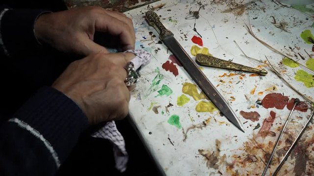 artist restorer working on restoring the old Persian knife