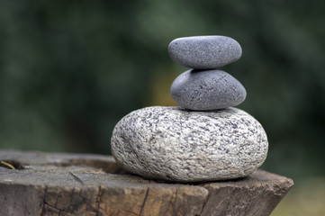 Fototapeta na wymiar Three zen stones pile on wooden stump, white and grey meditation pebbles tower