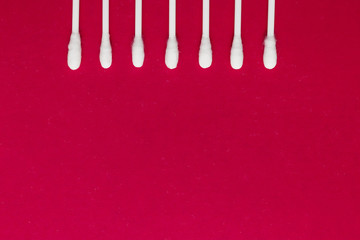 Hygienic, cotton buds on a red background. The concept of hygiene, cleanliness.
