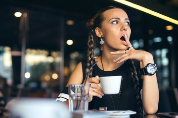 Woman with pigtails drinking coffee in trendy cafe.