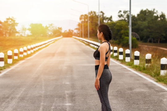 Asian sport woman in sportwear standing on road. Fitness woman resting after workout session.
