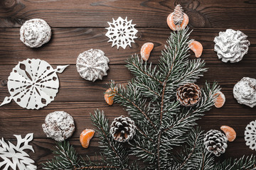 Brown wood background. Slice of mandarins. Fir tree and cones. Sweets. Christmas and New Year decorations. Xmas and Happy New Year composition. Flat lay, top view