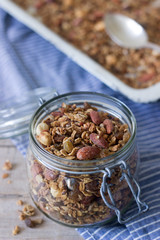 Homemade granola in a glass jar and on a baking sheet. Rustic style.