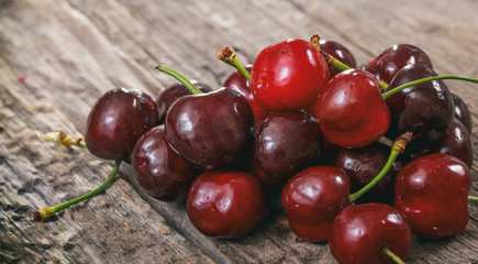 A heap of red cherries, on a wooden surface.