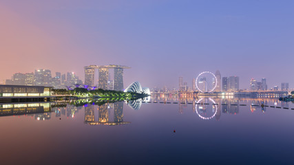 Naklejka premium Singapore skyline with CBD, Central Business District, Gardens by the Bay, Sands hotel and Flyer wheel reflecting in Marina Bay, at sunrise, from the Barrage.