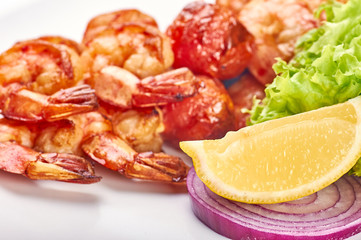 Appetizing fried shiny huge shrimp. Greens, lettuce, lemon, red onions as a side dish for royal prawns on the grill. Easy dietary healthy food for slimming people.