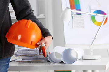 Man architect wearing suit holding helmet standing in office