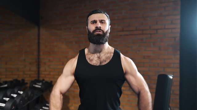 Strong man is pumping muscles at the gym, power exercises with dumbbells, athlete at fitness club, caucasian man with beard