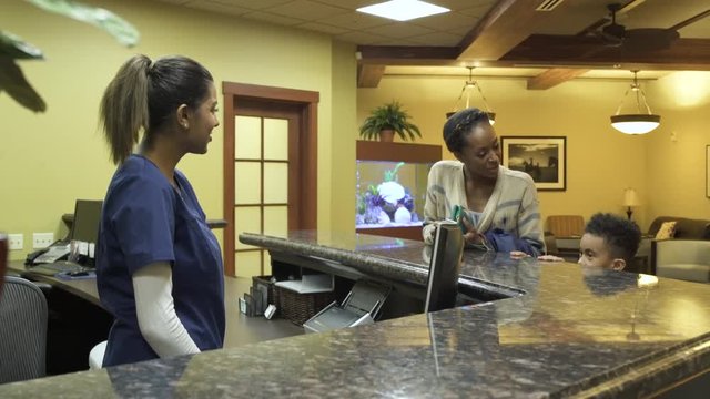 Medium shot of a mother and her son checking in at a health facility