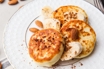 Delicious cottage cheese pancakes or syrniki with espresso on grey table