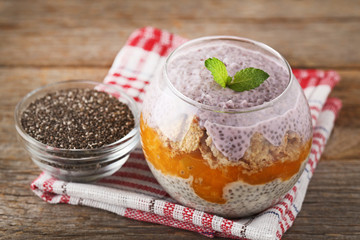Chia pudding with corn flakes in glass on wooden table