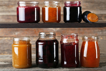 Glass jars with different kinds of jam on wooden table