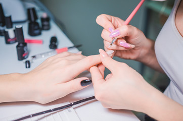 Obraz na płótnie Canvas Manicurist hand painting client's nails. Professional workplace