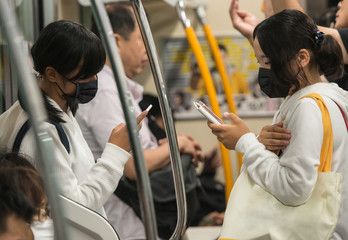 japanese girls with surgical masks on their face going to school by the undreground subway