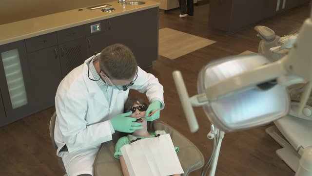 Jib shot of a dentist examining a girl