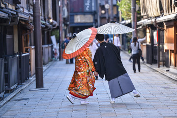 traditional japanese costumes kimono worn by bride and groom with original umbrellas taking photo shots on the marriage day in kyoto japan